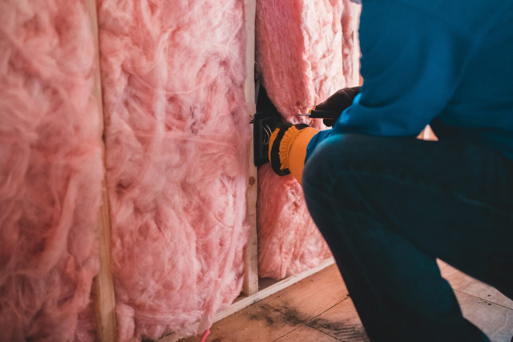 person installing pink rockwall insulation into a wall