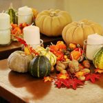 Autumn table decor with pumpkins, candles, nuts, and colourful leaves