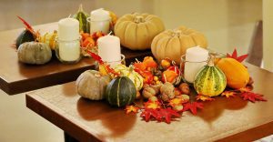 Autumn table decor with pumpkins, candles, nuts, and colourful leaves