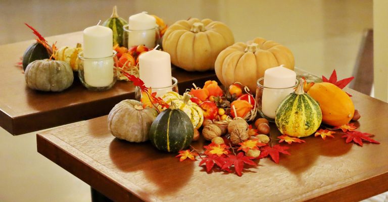 Autumn table decor with pumpkins, candles, nuts, and colourful leaves